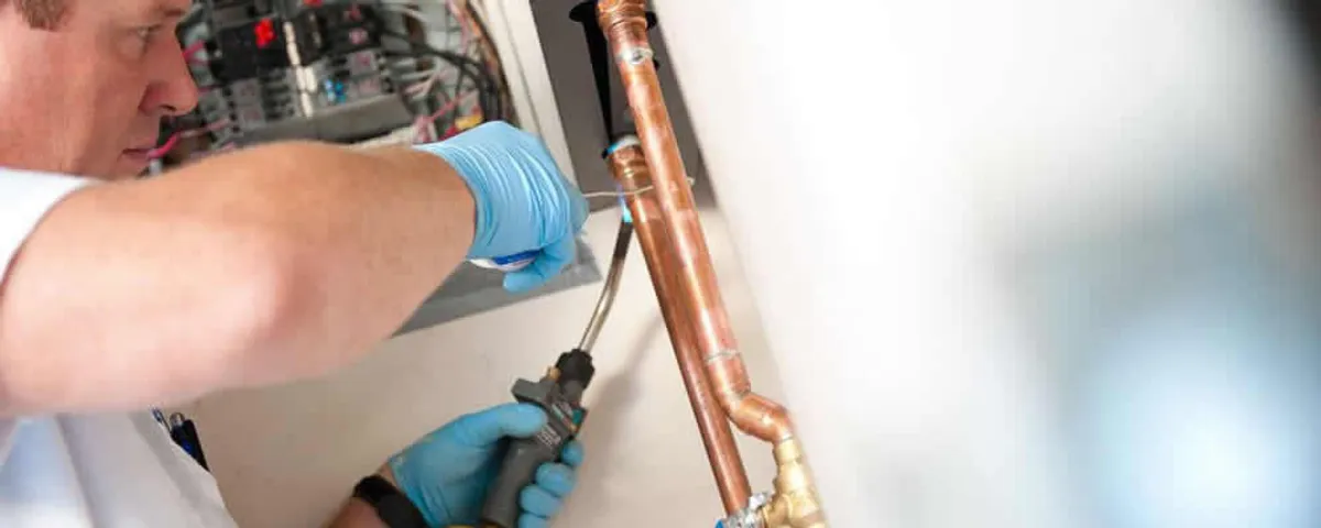 Water heater repair technician testing copper pipe connections and controls in Minneapolis, MN